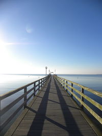 Pier over sea against clear blue sky