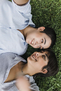 Smiling lesbian couple looking at each other lying on grass