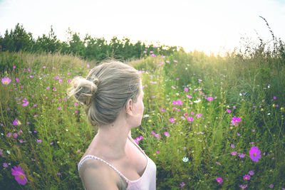 Rear view of woman with flowers in field