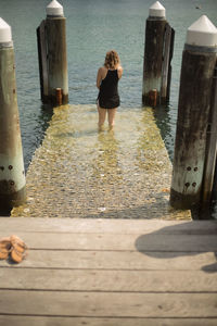 Rear view of woman standing on pier at beach