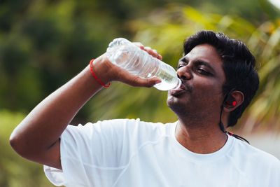 Close-up of man drinking water while standing outdoors