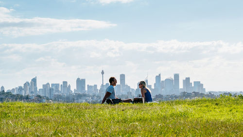 People on grassy field against cloudy sky