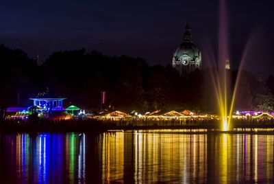 Illuminated building by lake at night