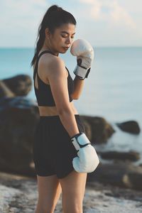 Side view of young woman exercising at beach