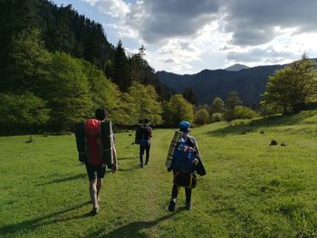 Rear view full length of hikers walking on field