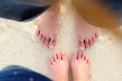 Low section of man and woman standing at beach