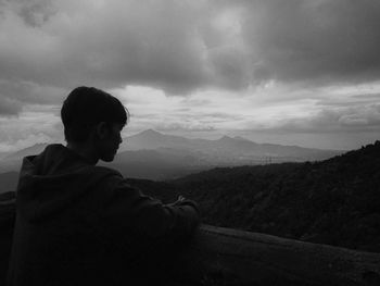 Man looking at mountain range against sky