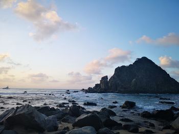 Scenic view of rocks on beach against sky