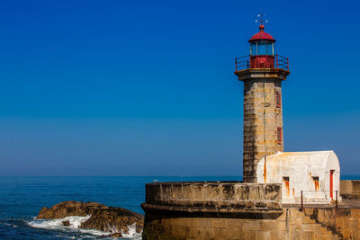 Lighthouse by sea against sky