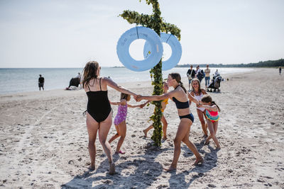 People enjoying at beach against sky