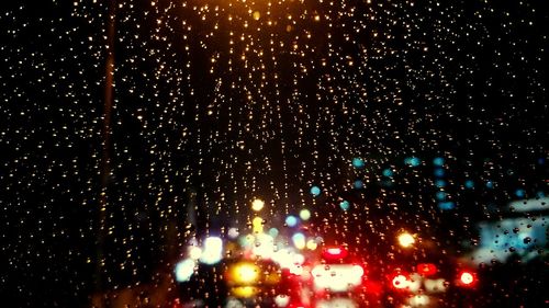 Illuminated street lights seen through wet window
