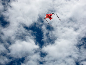 Low angle view of red paragliding against sky