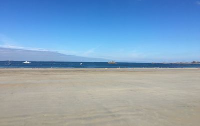 Scenic view of beach against clear blue sky