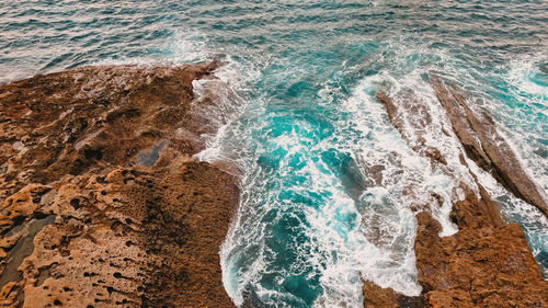 View of orange rocky shore and blue waves.