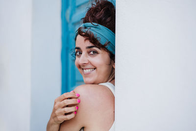 Portrait of a smiling young woman against wall