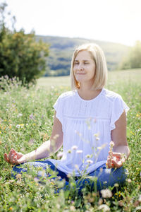 Smiling woman meditating on field