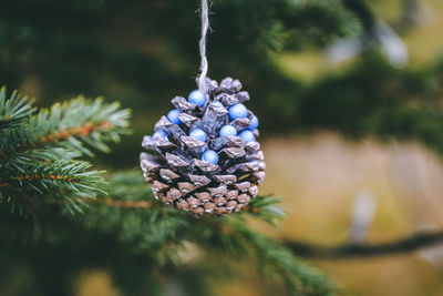 Pine cone with blue pearls on christmas tree. diy decoration ideas for children. environment