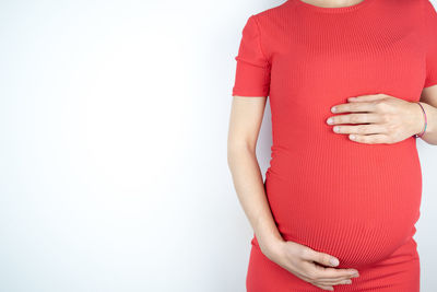 Midsection of woman touching red face against white background