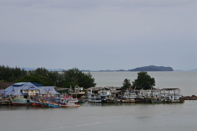 Sailboats in sea by houses against sky