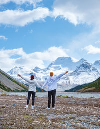 Rear view of people walking on field against sky