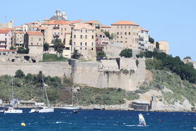 Sailboats in sea against buildings