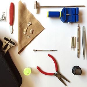 Directly above shot of watch maker tools on white table