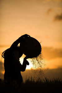 Silhouette woman working in farm during sunset
