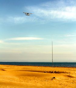 Airplane flying over sea against sky