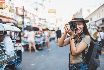 Portrait of smiling young woman standing on street in city