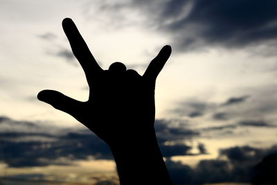 Cropped hand of person gesturing against sky