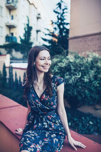 Cheerful optimistic brunette young woman in a flower dress on the street. spring or summer time 