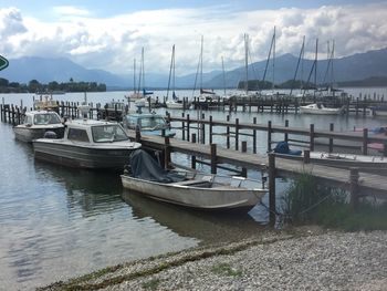 Sailboats moored at harbor against sky