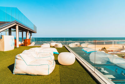 Lounge chairs by swimming pool at beach against clear sky