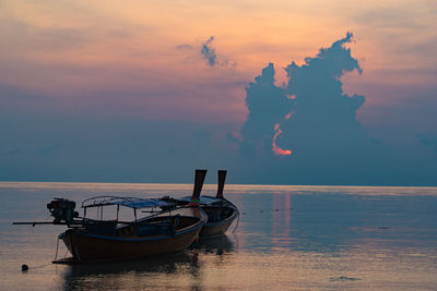 Boat moored in sea against sky during sunset