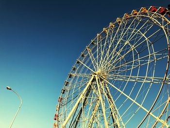 Low angle view of ferris wheel against clear blue sky