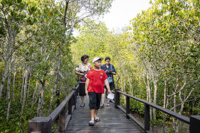 People walking on footbridge in forest