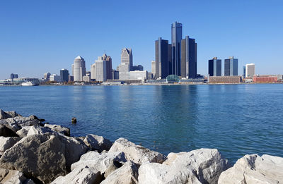 Sea by cityscape against clear sky