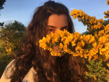 Close-up of young woman with yellow flowers in park