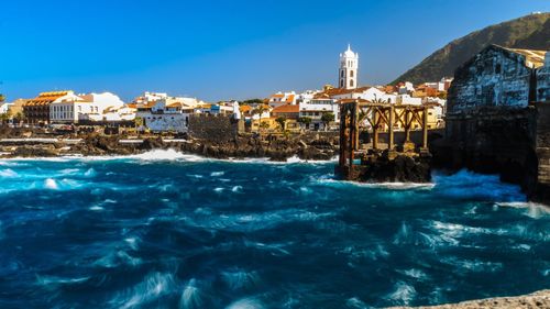 Buildings in sea against blue sky