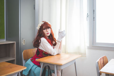 Portrait of young woman sitting on table at home