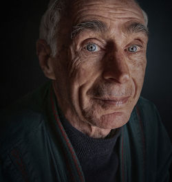 Close-up portrait of senior man against black background