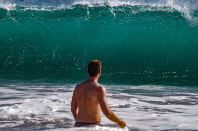 Rear view of shirtless man standing at beach