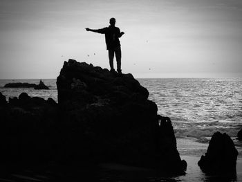 Man standing on cliff by sea