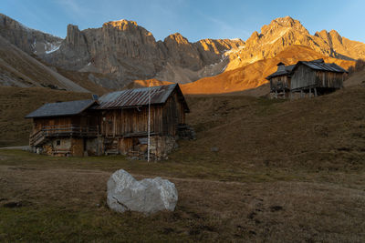 House on field by mountains against sky