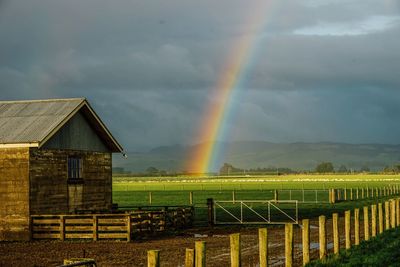 Scenic view of rainbow over field against sky
