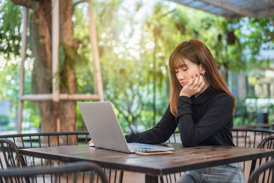 Woman looking away while sitting on table