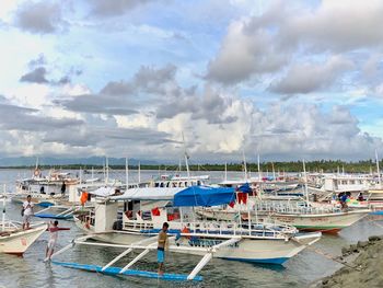 Boats moored at harbor against sky