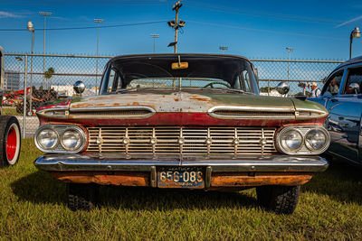 Abandoned car on field against blue sky