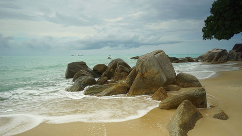 Rocks on beach against sky in tanjung pesona