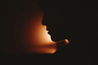 Close-up portrait of silhouette man against black background